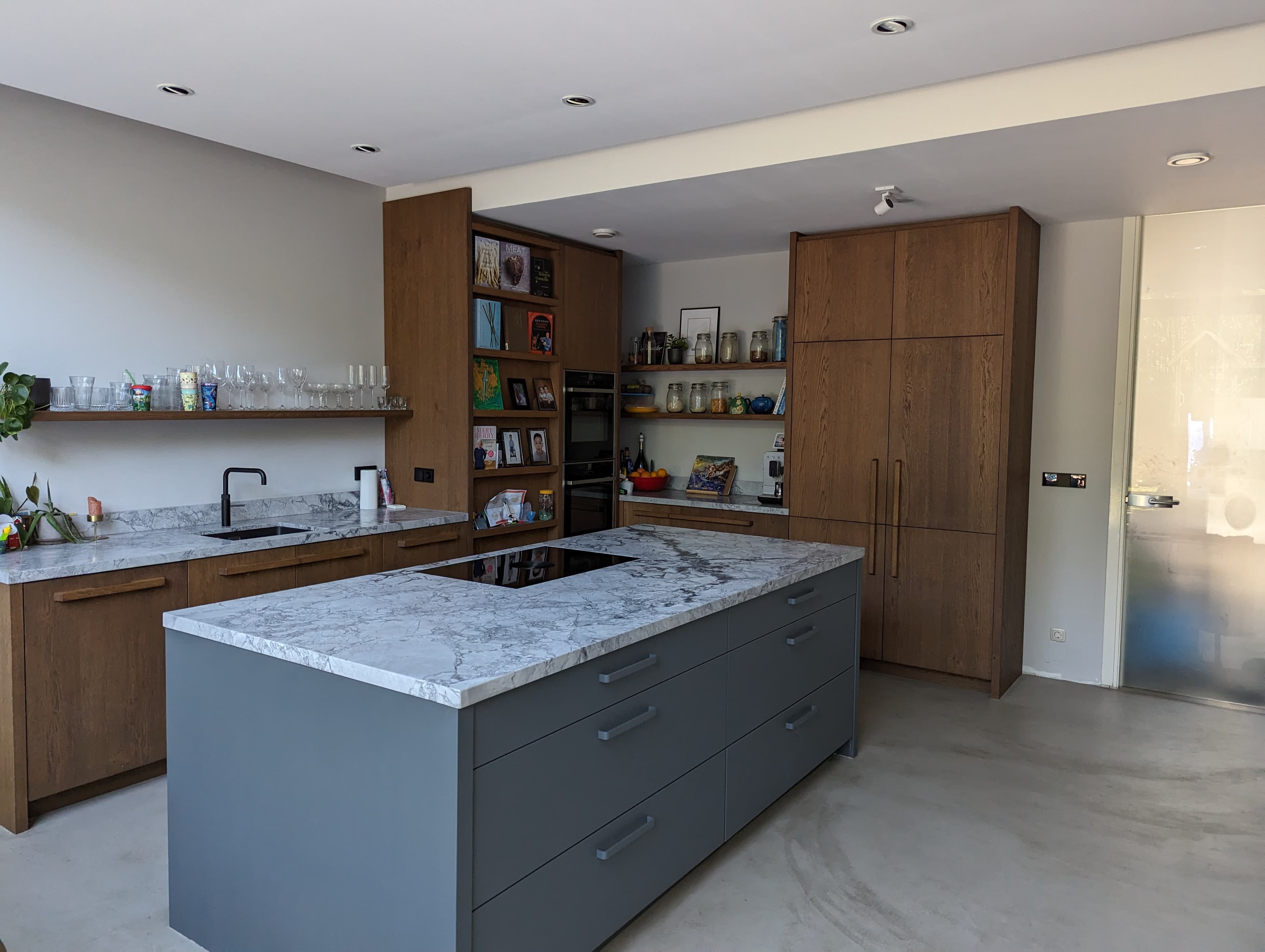 A warm minimalist kitchen with soft morning light and sage green cabinets